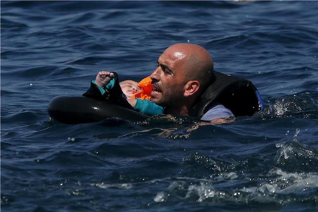 Παλεύοντας με τα κύματα για να σώσει ένα βρέφος. Η συγκλονιστική φωτογραφία του Άλκη Κωνσταντινίδη από το πρακτορείο Reuters